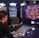 A person is seated at a slot machine console in a casino, focusing intently on the game displayed on the screen. The background shows several other illuminated gaming machines, adding a vibrant and colorful atmosphere to the scene.